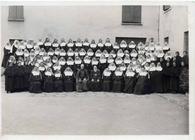 Sisters "Daughters of St Francis de Sales" of the Institute "San Giuseppe" of Lugo in the inner courtyard of the Institute, with Card. Federico Tedeschini and Monsignor Paolino Tribbioli (note the novices with white veil and the postulants in dark habit).