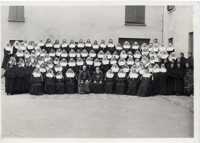 Suore “Figlie di San Francesco di Sales” dell’Istituto “San Giuseppe” di Lugo nel cortile interno dell’Istituto, col Card. Federico Tedeschini e Mons. Paolino Tribbioli (si notano le novizie col velo bianco e le postulanti in abito scuro). Set